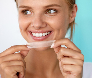 Female with whitening strip in her hands