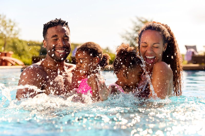 Patient with good dental health smiling with family in the pool 