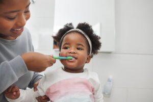 a child brushing their baby's teeth